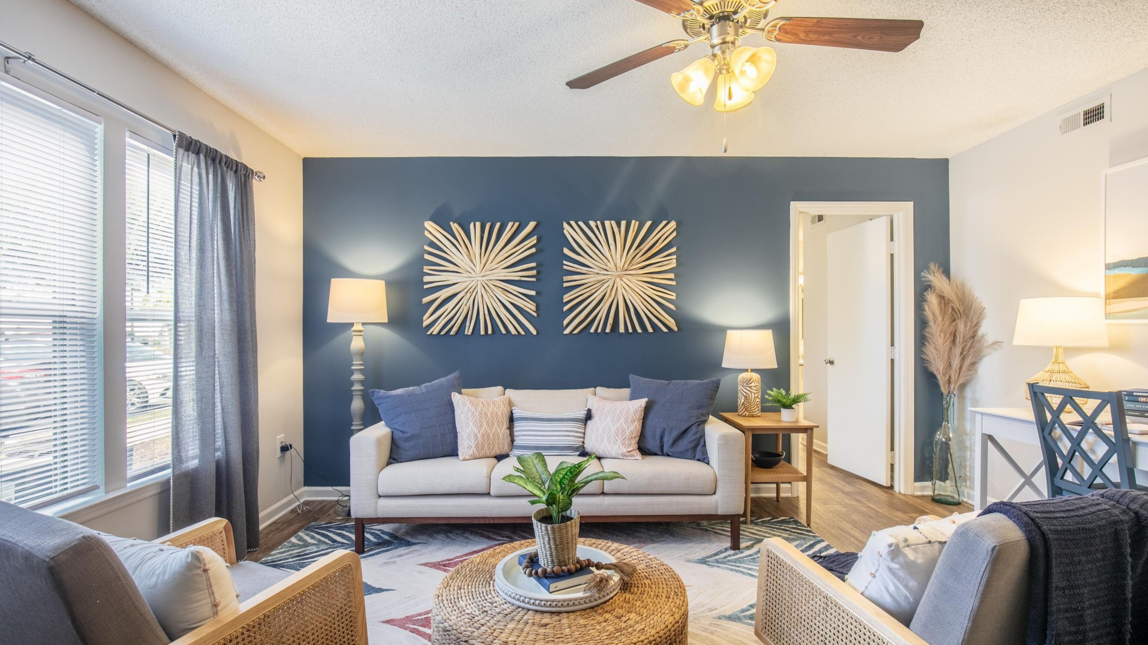 Hawthorne Commons apartment living room with large windows, furnished with a couch, coffee table, and chair